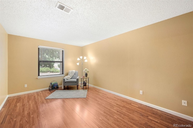 living area featuring a textured ceiling and light hardwood / wood-style floors