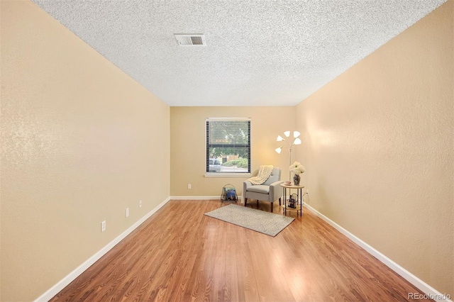 living area with a textured ceiling and light wood-type flooring