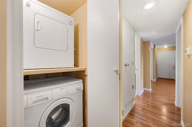 washroom featuring stacked washing maching and dryer, a textured ceiling, and light hardwood / wood-style floors