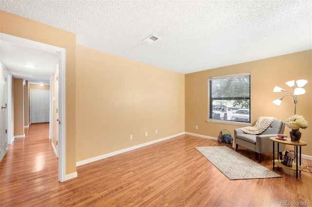 living area with a textured ceiling and light wood-type flooring