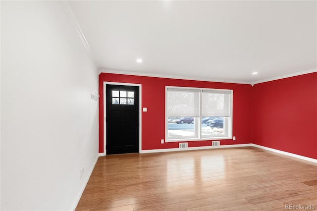 foyer with visible vents, light wood-style floors, baseboards, and ornamental molding