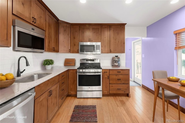 kitchen featuring a sink, stainless steel appliances, tasteful backsplash, and light wood-style floors