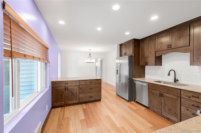 kitchen featuring a sink, recessed lighting, stainless steel appliances, light wood finished floors, and decorative backsplash