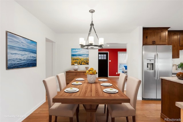 dining space featuring baseboards, an inviting chandelier, and light wood-style flooring