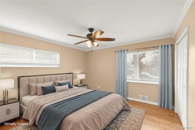 bedroom with visible vents, multiple windows, light wood-style floors, and ornamental molding