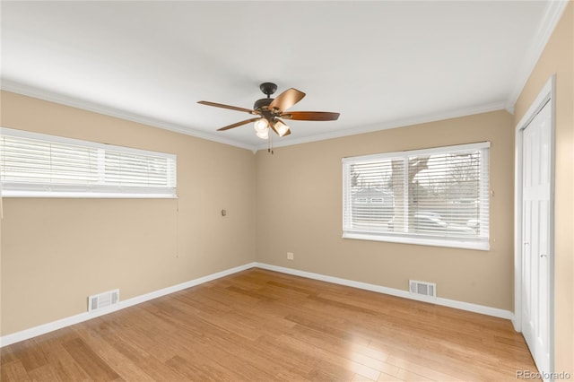 empty room featuring visible vents, light wood-style floors, and a healthy amount of sunlight