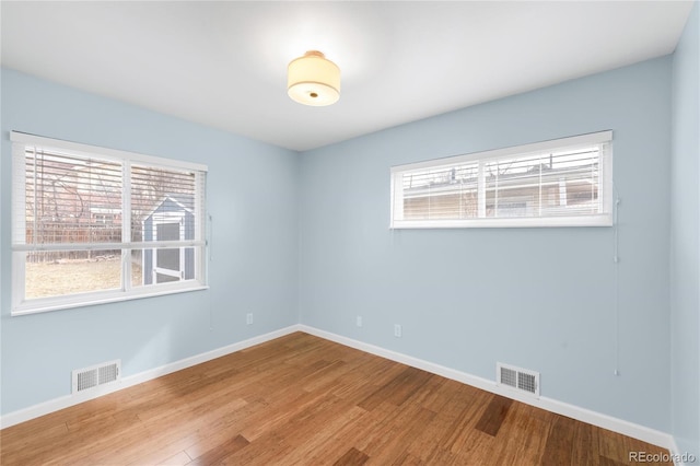 spare room featuring visible vents, baseboards, and wood finished floors