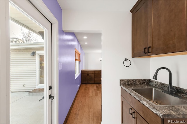 kitchen featuring dark stone countertops, recessed lighting, light wood-style floors, and a sink