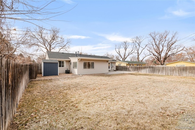 rear view of house featuring an outbuilding, a patio area, a storage unit, and a fenced backyard