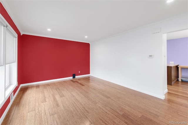 unfurnished room with ornamental molding, an accent wall, baseboards, and wood finished floors