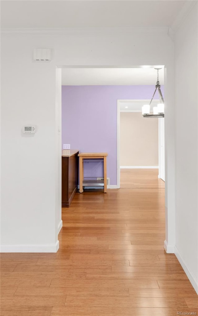 interior space with baseboards, light wood finished floors, and ornamental molding