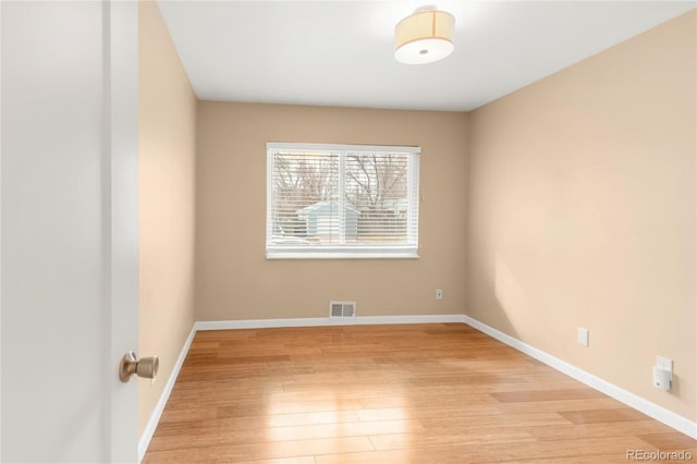 empty room featuring visible vents, baseboards, and light wood finished floors