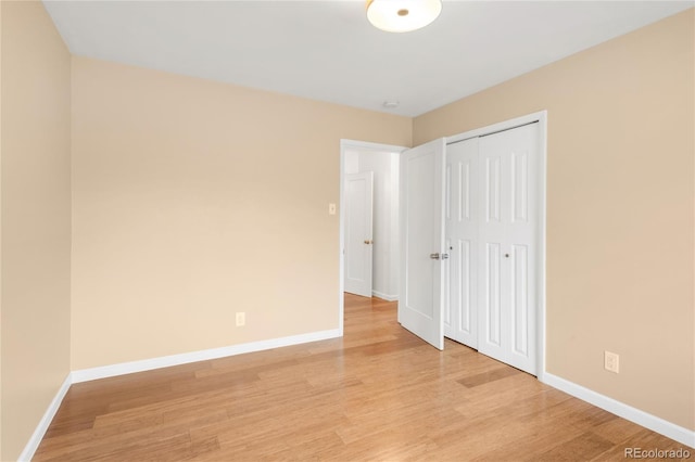 unfurnished bedroom featuring a closet, baseboards, and light wood-style floors