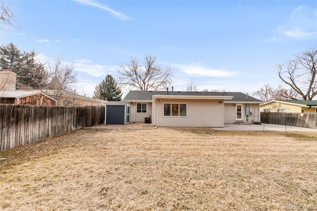 back of property with a storage unit, a lawn, a fenced backyard, an outdoor structure, and a patio area