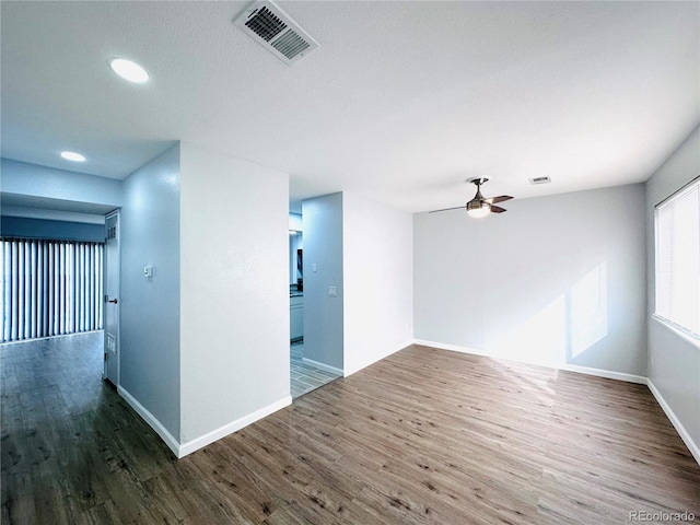 unfurnished room with ceiling fan, visible vents, baseboards, and wood finished floors