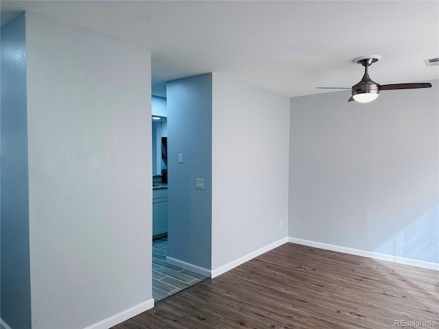 unfurnished room with ceiling fan, visible vents, baseboards, and wood finished floors