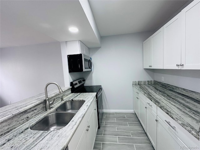 kitchen with white cabinets, light stone counters, appliances with stainless steel finishes, and a sink