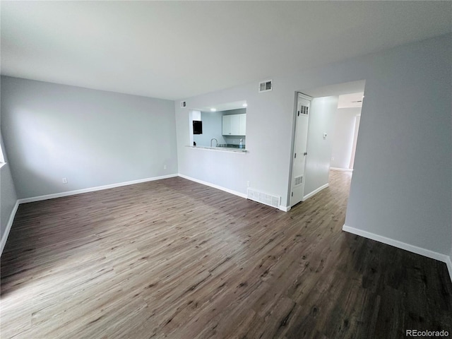 unfurnished living room featuring dark wood-style floors, visible vents, and baseboards