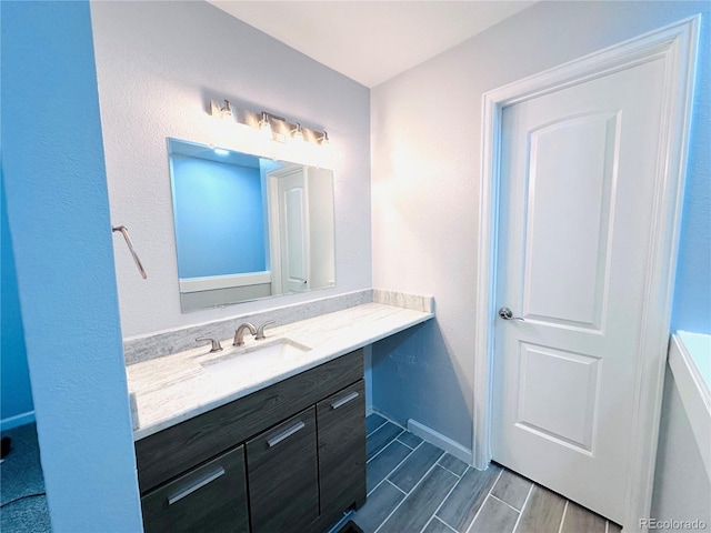 bathroom featuring baseboards, wood tiled floor, and vanity