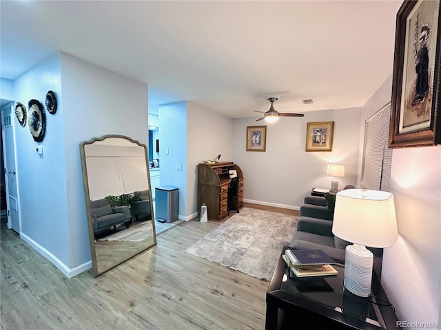 living area featuring light wood-style floors, visible vents, a ceiling fan, and baseboards