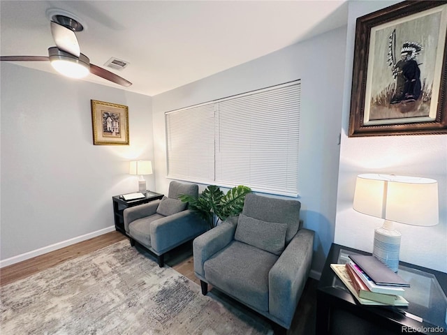 living area with wood finished floors, visible vents, baseboards, and ceiling fan