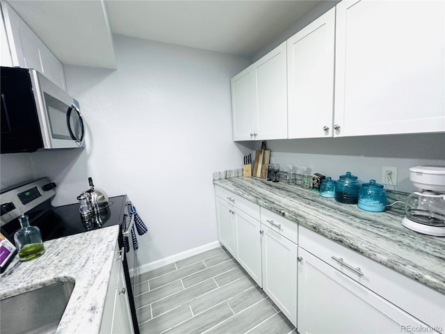 kitchen with white cabinets, baseboards, stainless steel appliances, and light stone counters