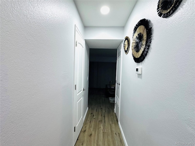 corridor with wood finished floors and baseboards
