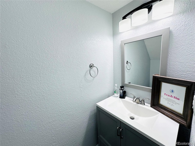 bathroom with a textured wall and vanity