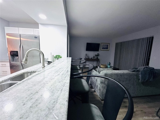 interior space with white cabinets, stainless steel refrigerator with ice dispenser, and a sink