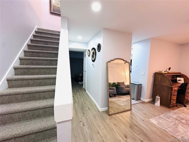 stairway with baseboards, wood finished floors, and recessed lighting