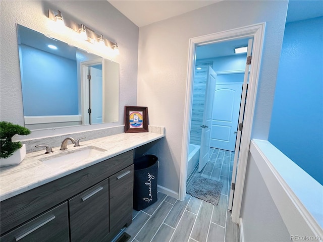 full bathroom featuring baseboards, wood tiled floor, and vanity