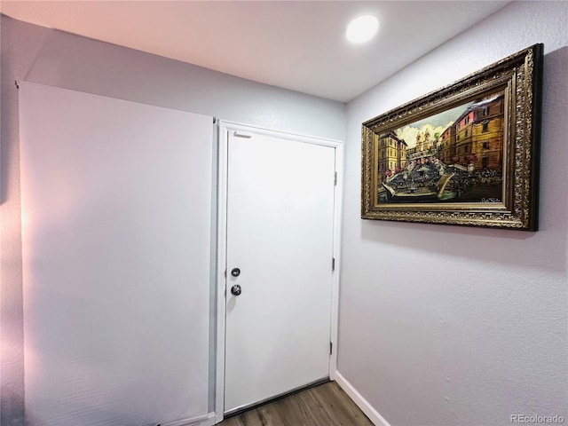 doorway to outside featuring baseboards and dark wood-type flooring