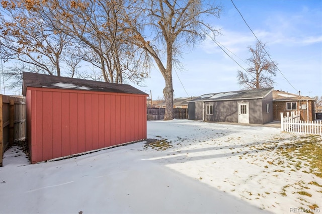 snowy yard featuring a storage unit