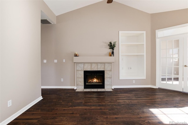 unfurnished living room featuring lofted ceiling with beams, a tile fireplace, dark hardwood / wood-style floors, and built in shelves