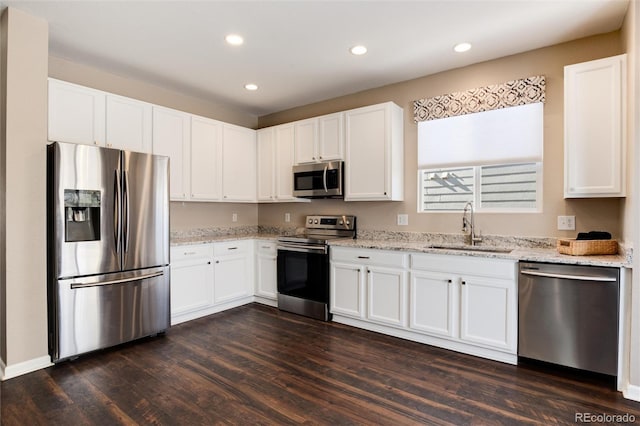 kitchen featuring stainless steel appliances, light stone countertops, sink, and white cabinets