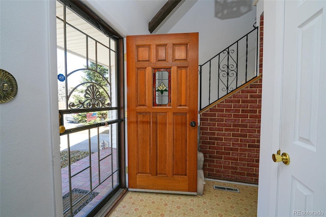 foyer entrance featuring visible vents, light floors, brick wall, and floor to ceiling windows