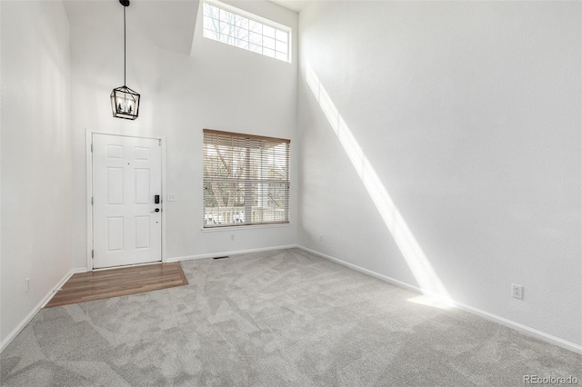 foyer entrance featuring carpet floors, baseboards, and a towering ceiling