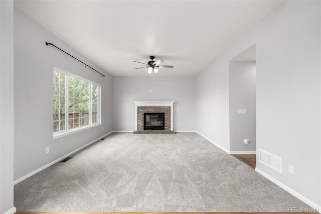 unfurnished living room with carpet, a ceiling fan, a brick fireplace, and visible vents