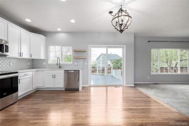 kitchen with white cabinets, a notable chandelier, a sink, light countertops, and stainless steel appliances