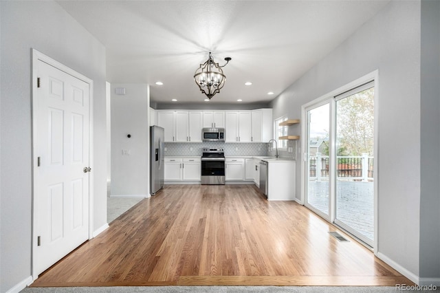 kitchen with a sink, appliances with stainless steel finishes, light wood-style floors, and visible vents