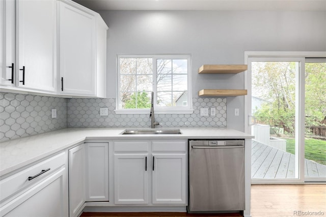 kitchen with white cabinets, light countertops, a sink, and dishwasher