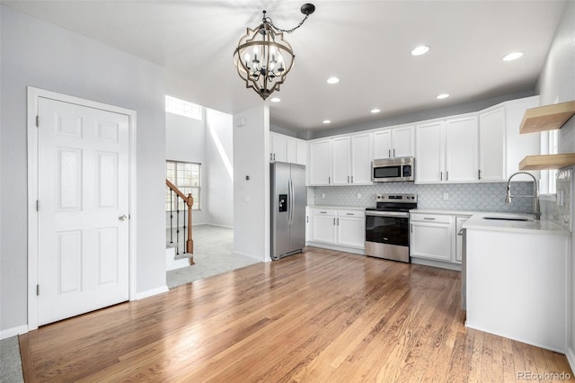 kitchen featuring tasteful backsplash, open shelves, a sink, a notable chandelier, and stainless steel appliances