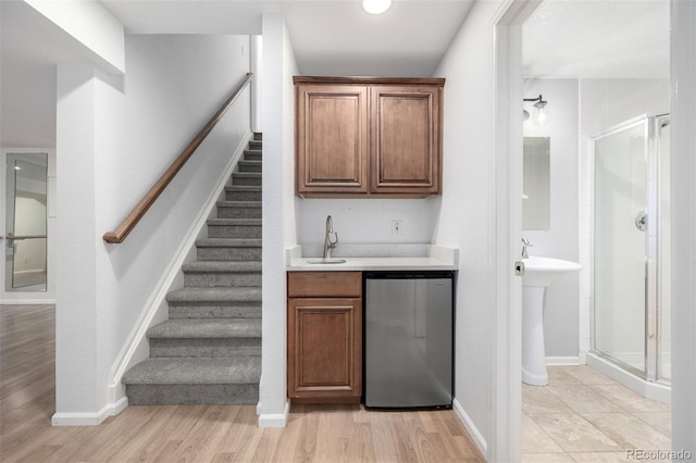 bar featuring fridge, a sink, light wood-style floors, stairs, and wet bar