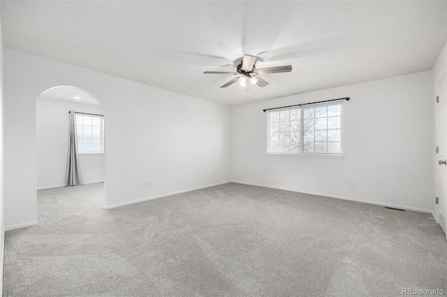 spare room with arched walkways, ceiling fan, carpet, and baseboards