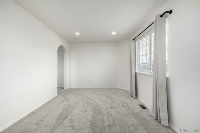 spare room featuring carpet flooring, arched walkways, recessed lighting, baseboards, and visible vents