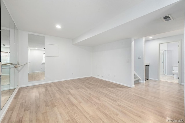 interior space featuring baseboards, visible vents, stairway, and light wood-style floors
