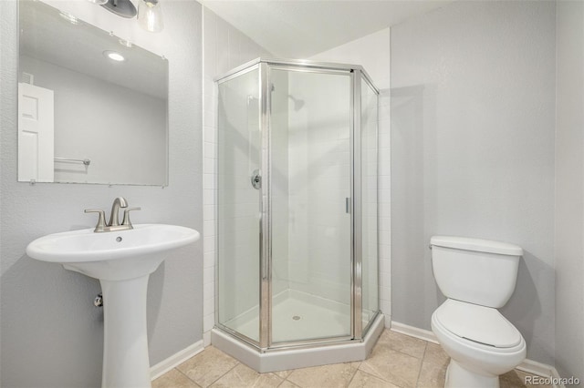 bathroom featuring tile patterned floors, baseboards, a shower stall, and toilet