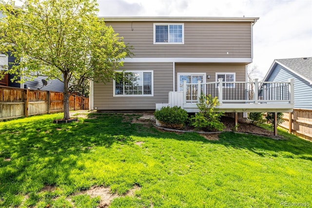 back of property featuring a yard, a wooden deck, and a fenced backyard
