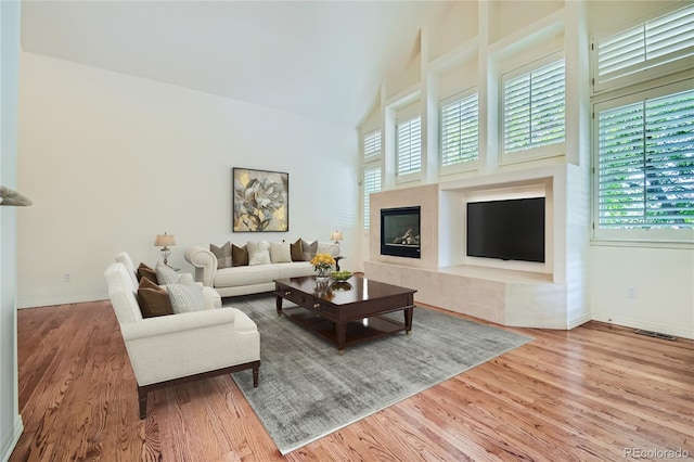 living room featuring light wood-type flooring and high vaulted ceiling