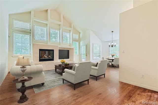 living room featuring plenty of natural light, wood-type flooring, a fireplace, and a towering ceiling